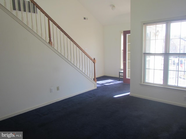 entryway featuring visible vents, baseboards, vaulted ceiling, stairway, and dark colored carpet