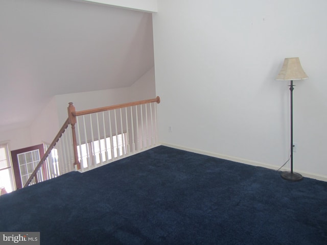 spare room featuring dark colored carpet and baseboards