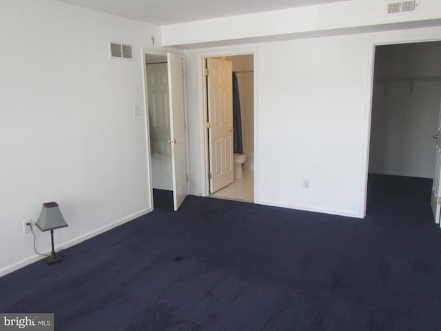 unfurnished bedroom with a walk in closet, a closet, visible vents, and baseboards