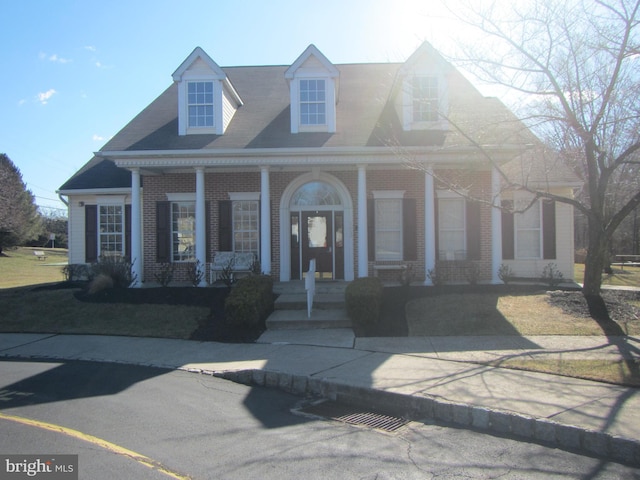 cape cod house with a porch and brick siding