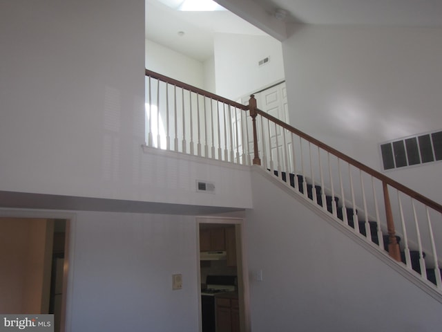 stairway with visible vents and a high ceiling