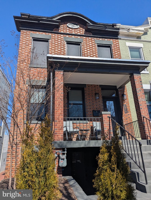 townhome / multi-family property with brick siding and covered porch