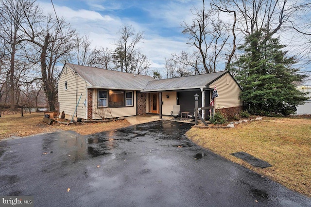 ranch-style house with aphalt driveway, a front yard, and brick siding