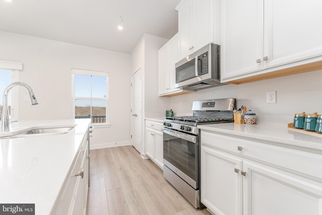 153 Glory Maple Ln, Downingtown, PA 19335 - kitchen with light countertops, stainless steel appliances, light wood-style floors, white cabinetry, and a sink