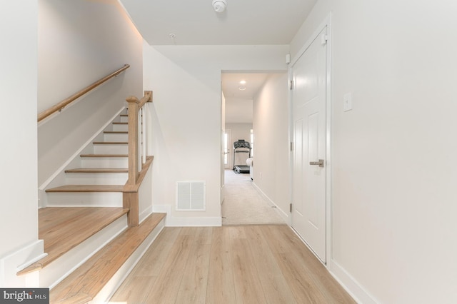 interior space featuring visible vents, baseboards, light wood-style floors, and stairway