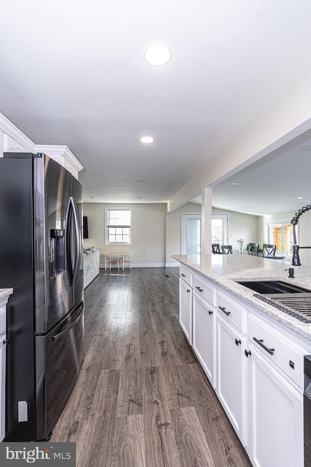 kitchen featuring dark wood finished floors, a sink, stainless steel fridge, white cabinetry, and open floor plan