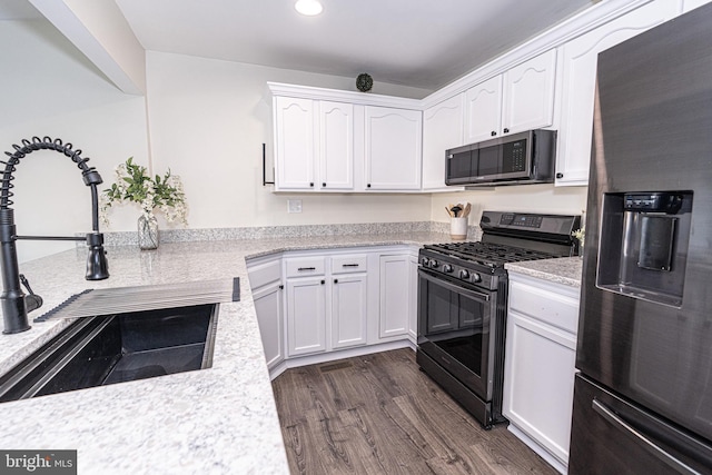 kitchen featuring a sink, stainless steel appliances, dark wood-type flooring, and white cabinetry