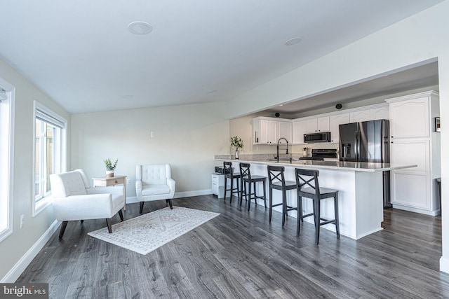 kitchen with white cabinets, black range, a peninsula, and a kitchen breakfast bar