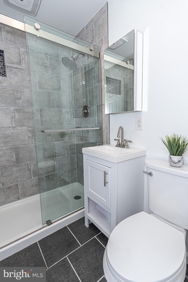 full bath with toilet, a stall shower, vanity, and tile patterned flooring