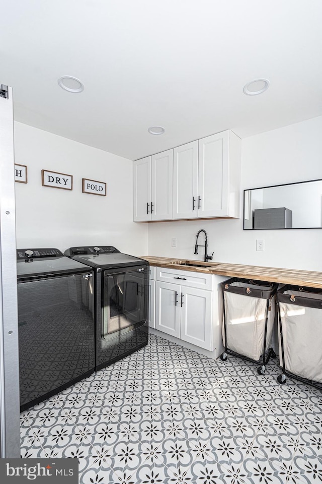 washroom with a sink, washer and dryer, recessed lighting, cabinet space, and light floors