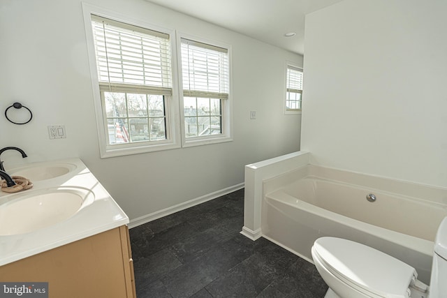 bathroom featuring toilet, a bath, baseboards, and a sink