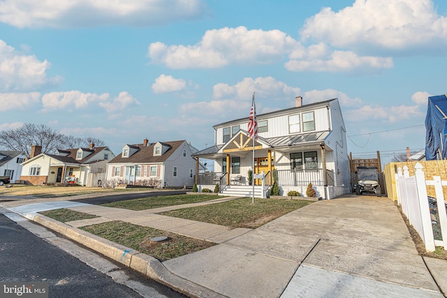 view of front facade with a residential view, covered porch, metal roof, driveway, and a standing seam roof