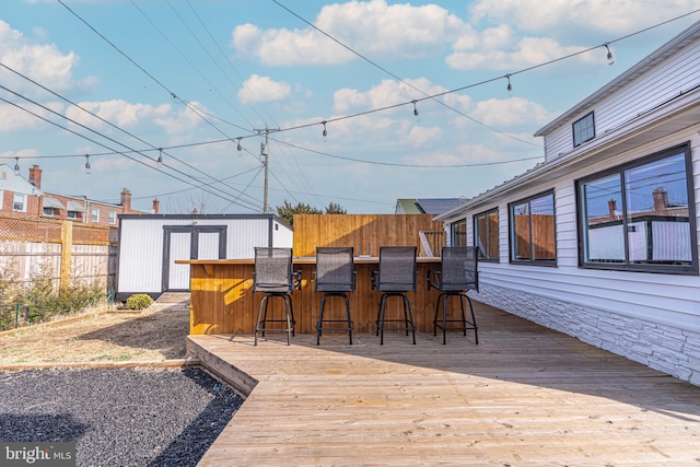 wooden deck with outdoor dry bar, a fenced backyard, a storage unit, and an outdoor structure