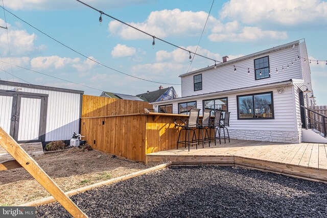 back of property featuring an outdoor structure, a deck, a storage shed, and fence