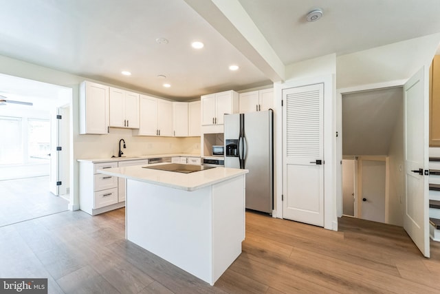 kitchen featuring light countertops, a sink, white cabinets, light wood-style flooring, and black appliances