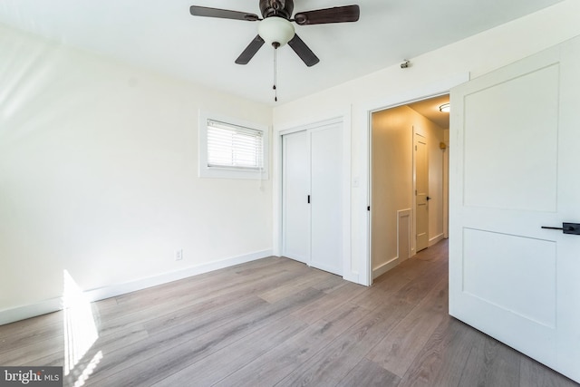 unfurnished bedroom featuring light wood-style flooring, baseboards, a closet, and ceiling fan