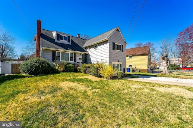 view of property exterior with a chimney, fence, and a lawn