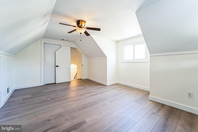 additional living space featuring lofted ceiling, baseboards, visible vents, a ceiling fan, and wood finished floors