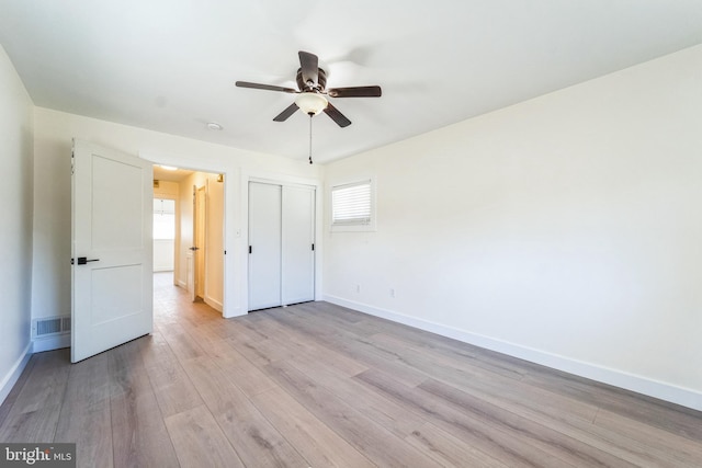 unfurnished bedroom featuring light wood-style flooring, a closet, baseboards, and visible vents
