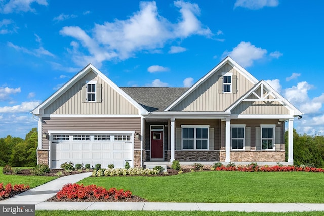 craftsman-style house with stone siding, a shingled roof, a front lawn, and board and batten siding