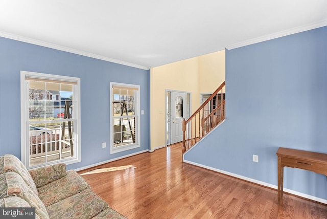 living room with baseboards, crown molding, stairway, and wood finished floors