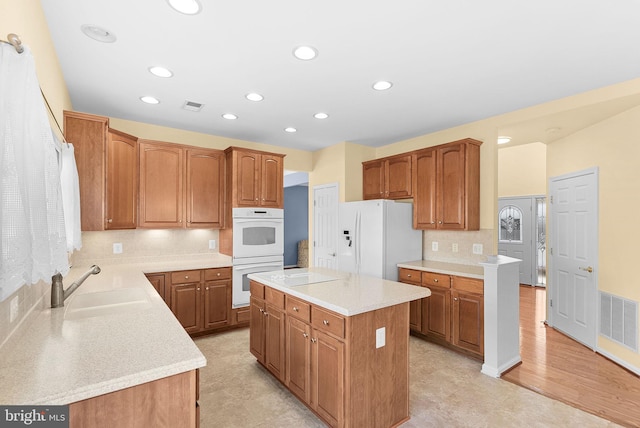 kitchen with white appliances, a kitchen island, visible vents, and light countertops