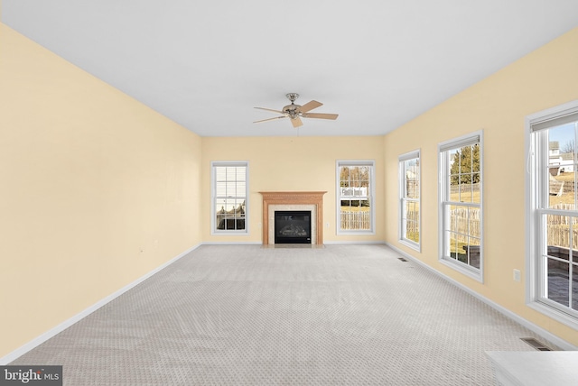 unfurnished living room featuring baseboards, visible vents, a ceiling fan, light colored carpet, and a fireplace with flush hearth