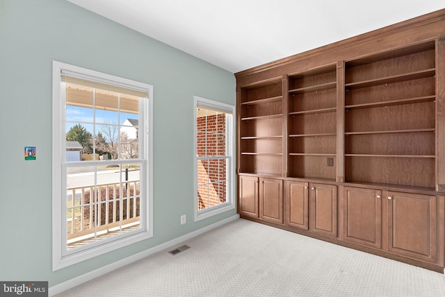 empty room featuring light colored carpet, visible vents, and baseboards