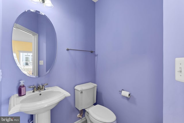 bathroom featuring a sink, toilet, and baseboards