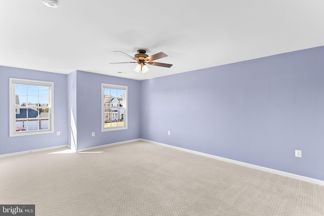 carpeted spare room with visible vents, ceiling fan, and baseboards