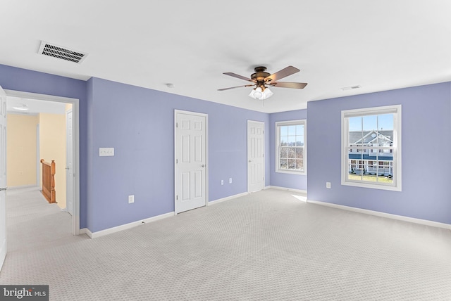 unfurnished bedroom featuring light carpet, multiple closets, visible vents, and baseboards