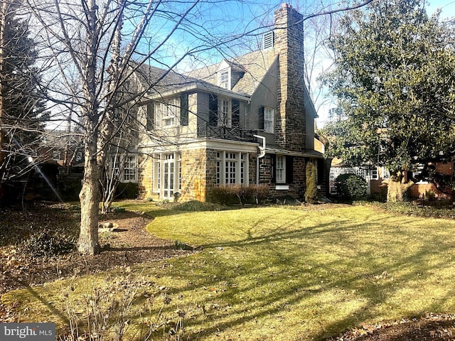 view of side of property with a yard, stone siding, and a chimney