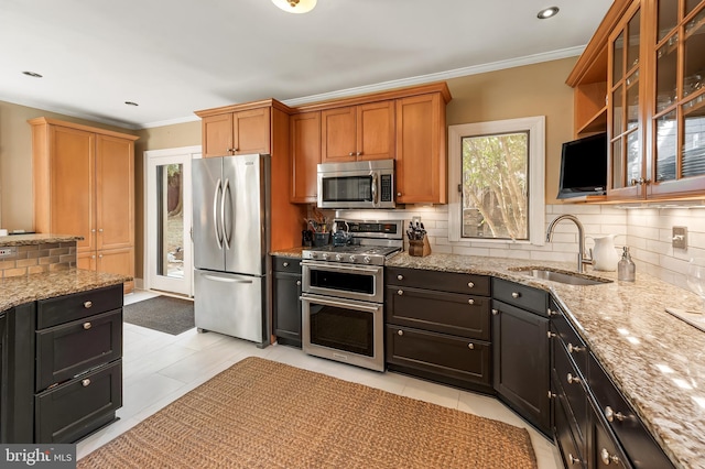kitchen with tasteful backsplash, light stone countertops, stainless steel appliances, and a sink