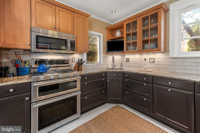 kitchen featuring a sink, light stone counters, backsplash, and appliances with stainless steel finishes