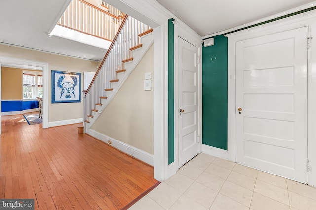 entryway featuring stairway, light wood-type flooring, and baseboards