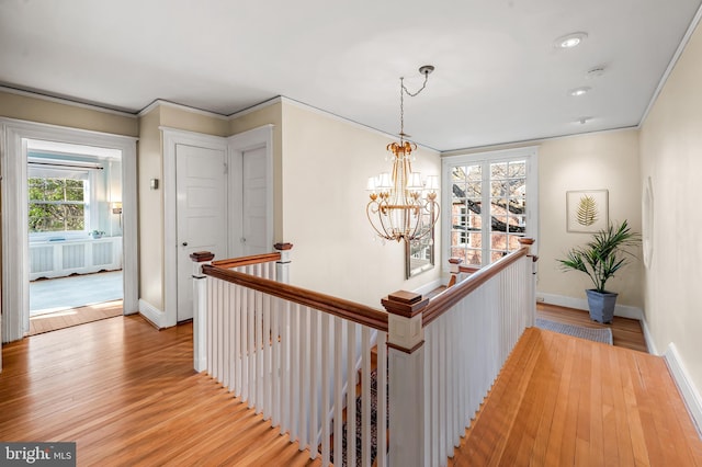 hallway featuring an upstairs landing, ornamental molding, and light wood finished floors