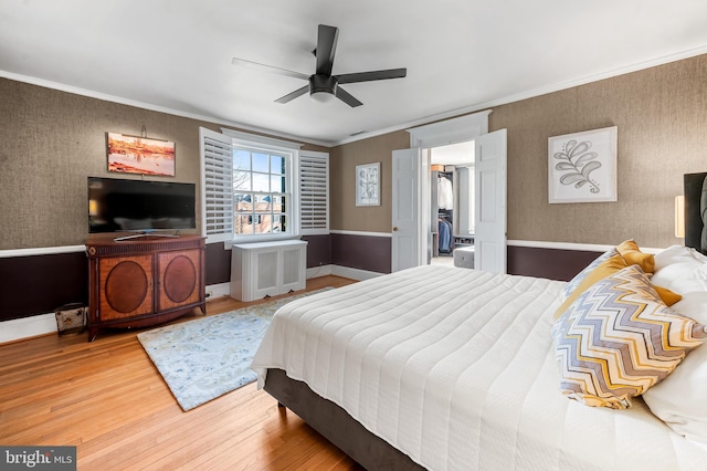 bedroom with wood finished floors, radiator, ornamental molding, and wallpapered walls