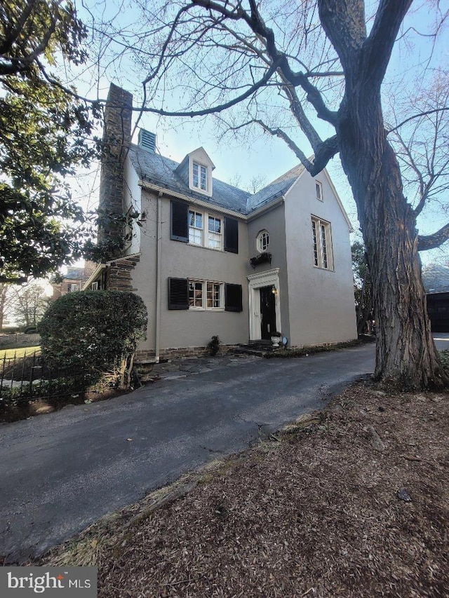 view of front facade featuring stucco siding and a chimney