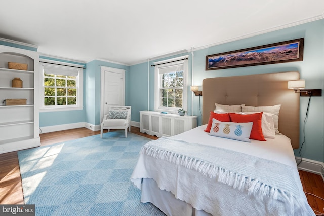 bedroom featuring crown molding, radiator heating unit, wood finished floors, and baseboards
