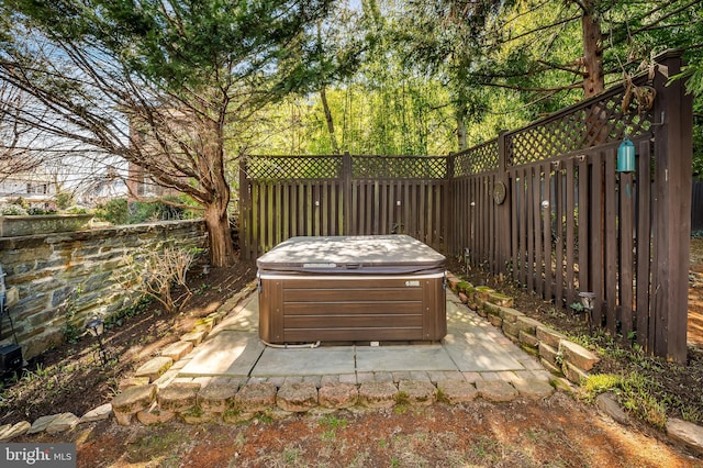 view of patio / terrace with a hot tub and fence