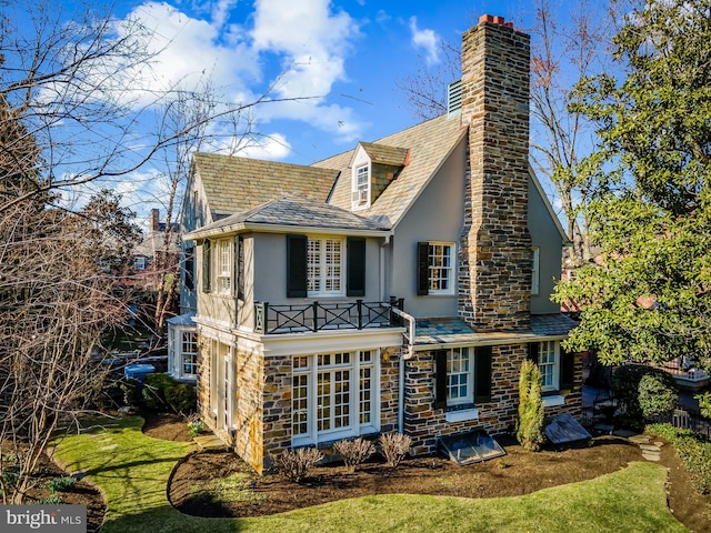 exterior space with a high end roof, stucco siding, stone siding, and a chimney