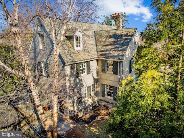 exterior space with stucco siding, a high end roof, and a chimney