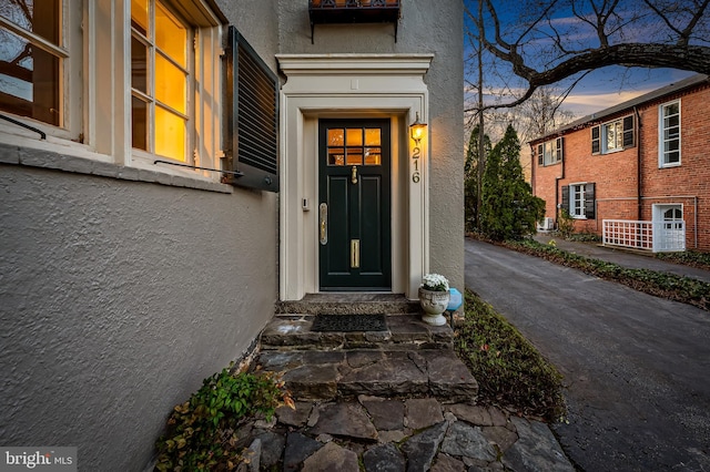 exterior entry at dusk featuring stucco siding