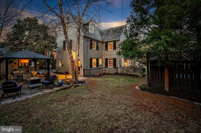 back of house with stucco siding, a high end roof, fence, a yard, and a patio area