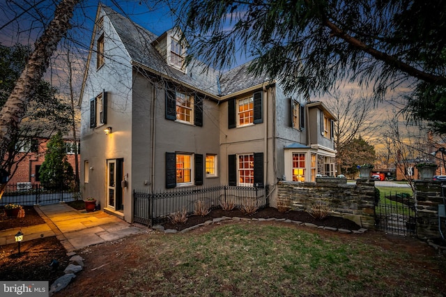 exterior space with a high end roof, a gate, a fenced front yard, and stucco siding