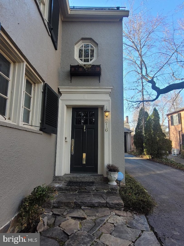 doorway to property featuring stucco siding and driveway