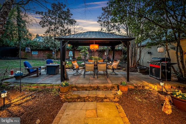 patio terrace at dusk with a gazebo, a grill, and an outdoor fire pit