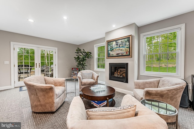 living room featuring a glass covered fireplace, recessed lighting, french doors, and baseboards