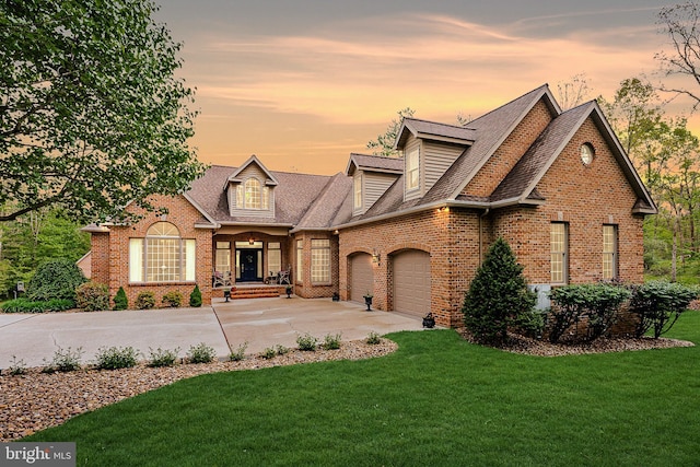 cape cod house featuring brick siding, a shingled roof, concrete driveway, a yard, and an attached garage