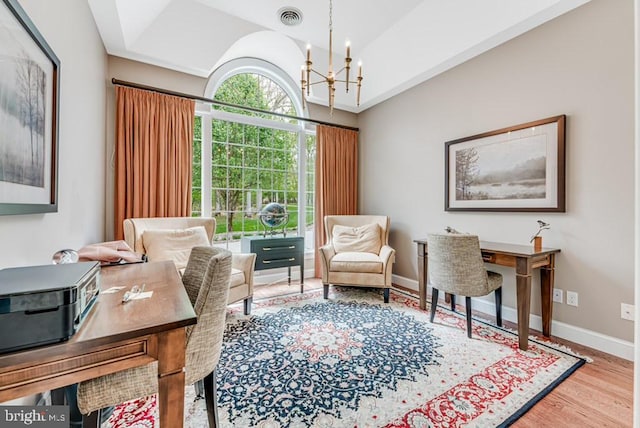 office space with visible vents, wood finished floors, baseboards, and a chandelier